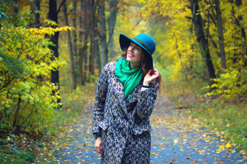 Pretty romantic girl in clothes walks in a park. The mood of autumn, leaf fall. Autumn fashion.