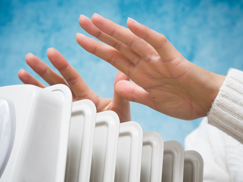 Female hands above the heater