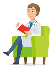 Obraz premium A young male doctor wearing a white suit sits on a sofa and is reading books