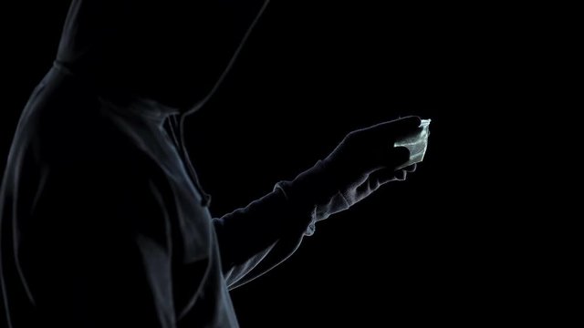 Drug addict male in hoodie looking at packet with amphetamine, addiction issue