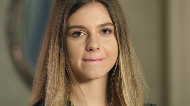 Portrait attractive woman with beautiful long hair and perfect make up biting and licking sensual lips and looking into camera close up