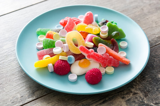 Colorful childs sweets and treats in plate on wooden table