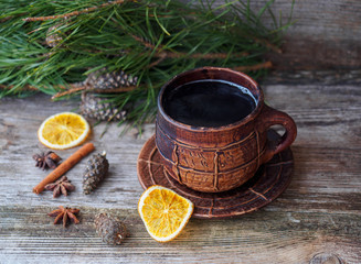 large coffee mug, pine branch with pine cones,dried oranges on a wooden table