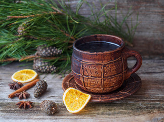 large coffee mug, pine branch with pine cones,dried oranges on a wooden table