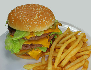 Triple Cheeseburger With Fires close up, on plate lettuce, cheese, stacked three high