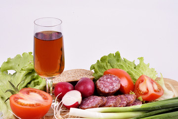 radish, onion, tomato, sausage, wine in a glass on a wooden background.