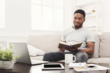 Happy young man at home reading book