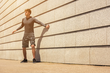 Fototapeta na wymiar Male jogger resting after morning run while standing against wall background with copy space area for your text message or advertising, young fit men taking break between training outdoors