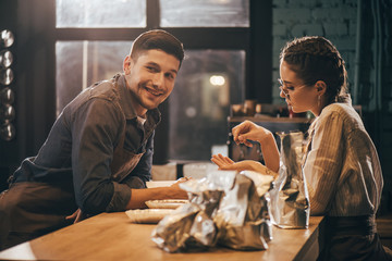 young colleagues standing at wooden table in coffee shop