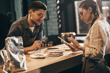 focused woman using tablet with young colleague near by at coffee shop