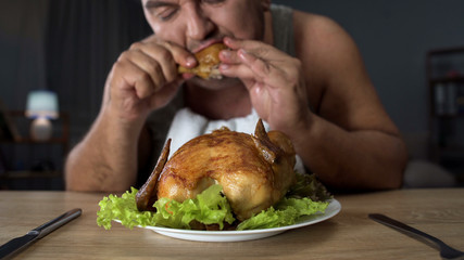 Plump male eating fatty fried chicken hungrily, high-calorie food and addiction