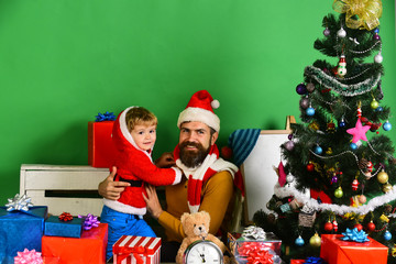 Santa and little assistant among gift boxes near Christmas tree