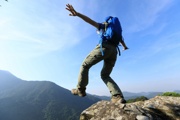 brave woman hiker walking to the cliff edge on mountain top