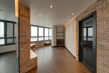 The room with big windows, a dark parquet and walls with a red brick
