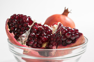 Piece of pomegranate in the bowl closeup on white background