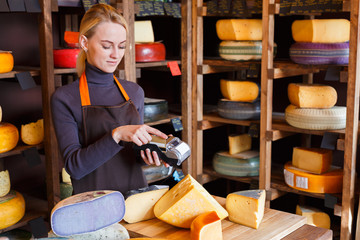 Customer paying for order of cheese in grocery shop.