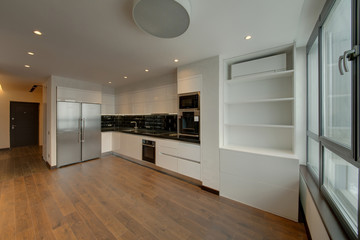 White kitchen with the big refrigerator and black inserts on a working surface
