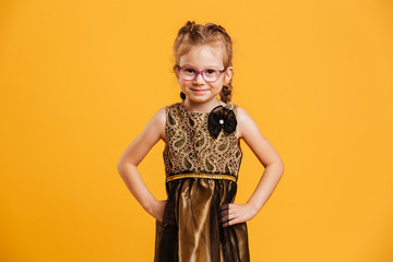 Cheerful girl child standing isolated over yellow