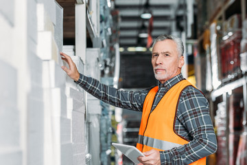 senior worker using digital tablet in storehouse