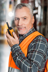 senior worker using walkie talkie in storage