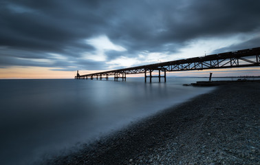 Fototapeta na wymiar Seascape with jetty during a dramatic cloudy sunset