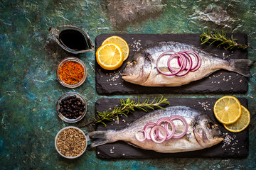 Dorada fish with vegetables, lemon, spices and greens on a blue background