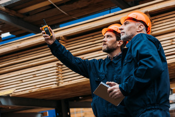 Naklejka na ściany i meble builders in helmets pointing with walkie talkie on construction