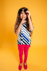 Fototapeta premium Little girl child wearing sunglasses showing silence gesture.
