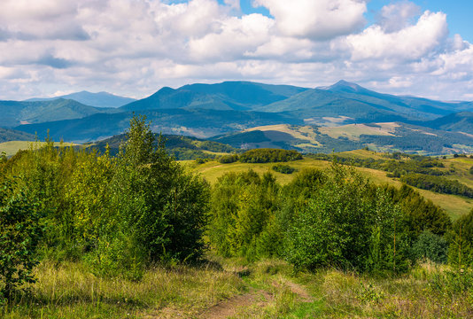 beautiful countryside of Crapathians in early autumn. forested hills and mountain ridge with high peak in the distance. lovely sunny weather with cloudy sky