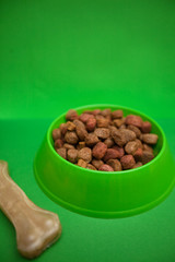 A bowl of dog food and a snack bone