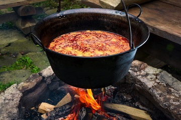 traditional Hungarian Goulash soup in cauldron. meal cooked outdoors on an open fire. delicious and healthy food popular in Central Europe - obrazy, fototapety, plakaty
