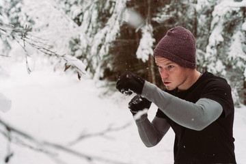 Young man shadow boxing in a forrest in Austria in the winter
