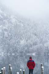 Young man standing on a bridge at a lake in Austria in the winter