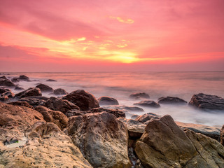 süßer Sonnenaufgang am Strand mit dem Felsen