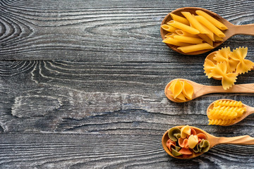 Various mix of pasta on wooden rustic background