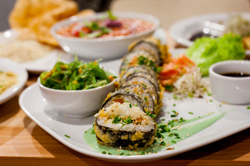 Healthy vegan table - a roll of sushi, wakame algae salad, chickpeas in tomatoes and falafel