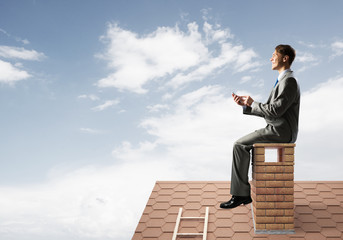 Businessman or student on brick roof smiling and making calls