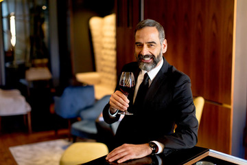 Handsome mature man tasting red wine