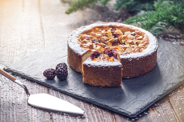 Homemade Christmas or New Year holiday berry pie with nuts on wooden table background. Concept of festive desserts