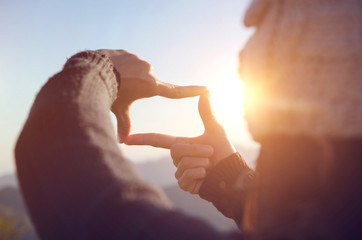 Close up of woman hands making frame gesture with sunrise on moutain, Female capturing the sunrise,...