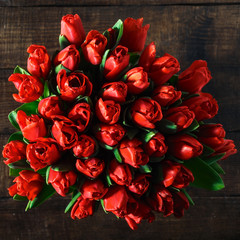 Bouquet of red tulips on dark wooden table top view