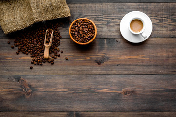 Fresh roasted coffee beans in bowl and scoop near canvas on dark wooden background top view copyspace