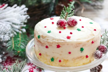 Homemade Xmas cake with white frosting sugar cranberries fir branches on Christmas frame, selective focus