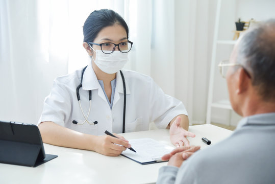 Asian Female Doctor talking to senior man patient.