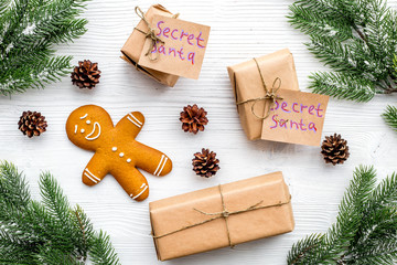 Christmas game Secret Santa. Gift boxes near spruce branch and gingerbread cookies on white background top view