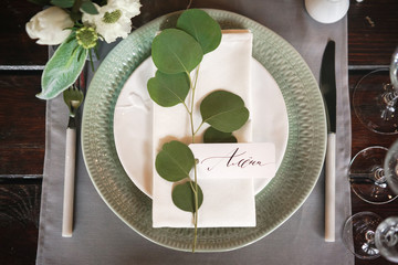 plate with a guest card signed by hand with caliber ink. Decoration of a table for a festive dinner.