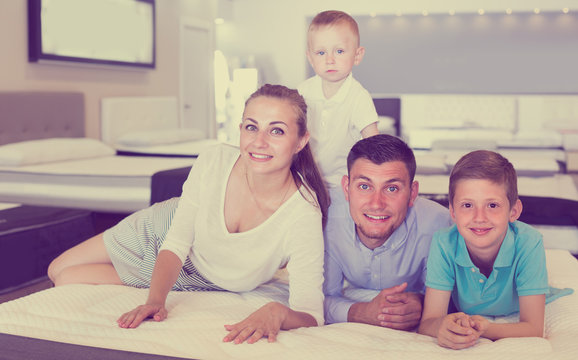 Father with mother and children are testing quality of mattress