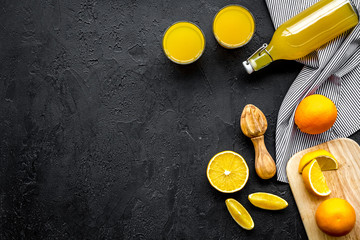 Squeeze juice from oranges. Juicer, slices of oranges, beverage in glass and bottle on black...