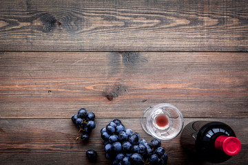 Fototapeta na wymiar Taste red wine. Bottle of red wine, glass and black grape on dark wooden background top view copyspace