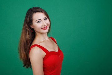Young beautiful girl in red dress isolated green background.